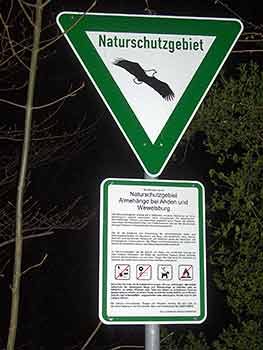 Ein Schild mit einem fliegenden Vogelbild und dem Text „Naturschutzgebiet“. Darunter ein rechteckiges Informationsschild mit ausführlichem Text und Symbolen zu den Vorschriften im Naturschutzgebiet.